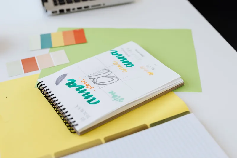 Close-up of design sketches and color swatches on a desk, the early planning stage before opening either Canva or Beacon&rsquo;s template editor