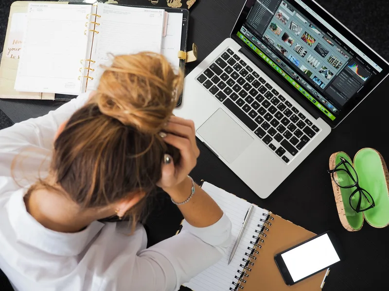 A woman working at her laptop, looking overwhelmed by a long document on screen