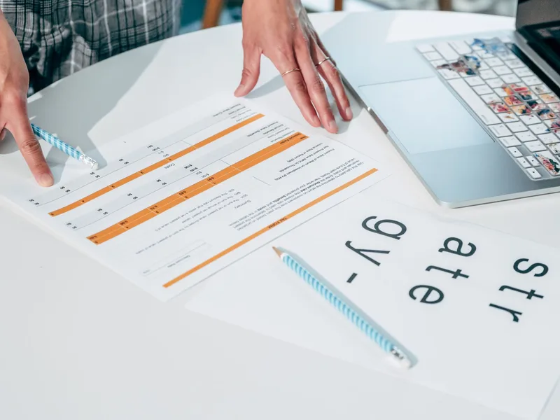 Hands reviewing business strategy documents on a desk, deciding between different approaches