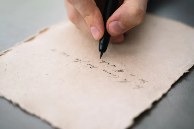 Close-up of a hand writing notes with a pen, representing the process of scoring each format-fit criterion by hand