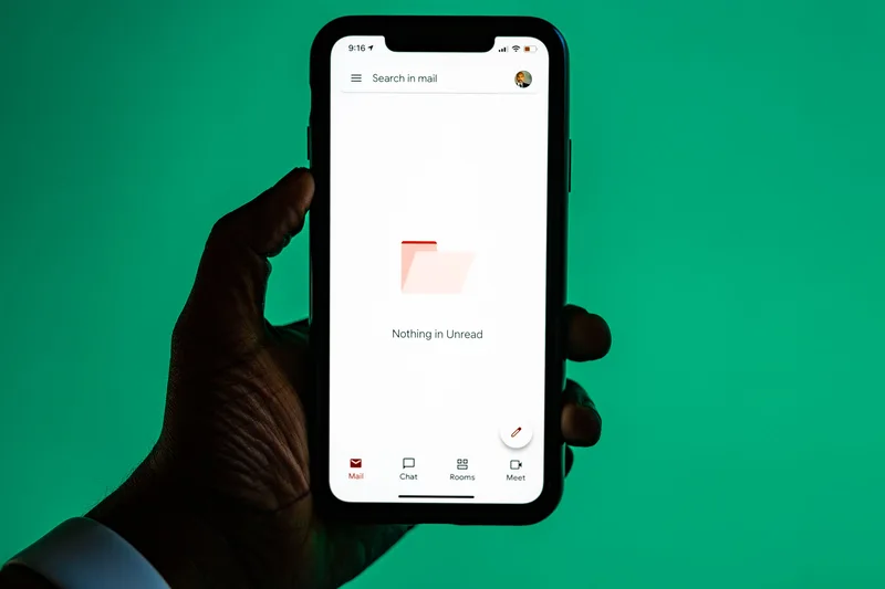 Hand holding a phone showing an empty mail inbox, representing the confirmation and delivery email test in a lead magnet audit