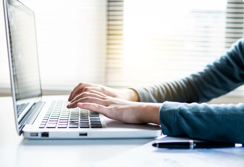 A person working at a computer writing an email newsletter, shown from the back in a home office setting