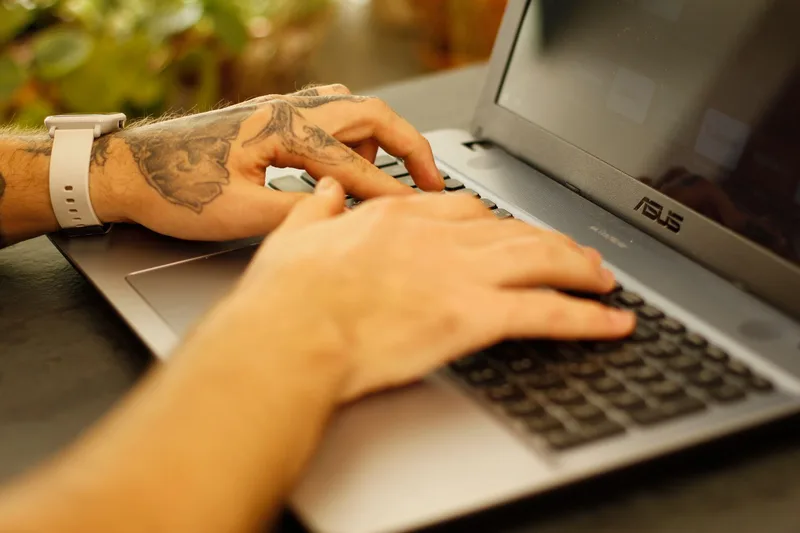 A person sitting at a desk writing on a laptop, composing a social media post about their lead magnet
