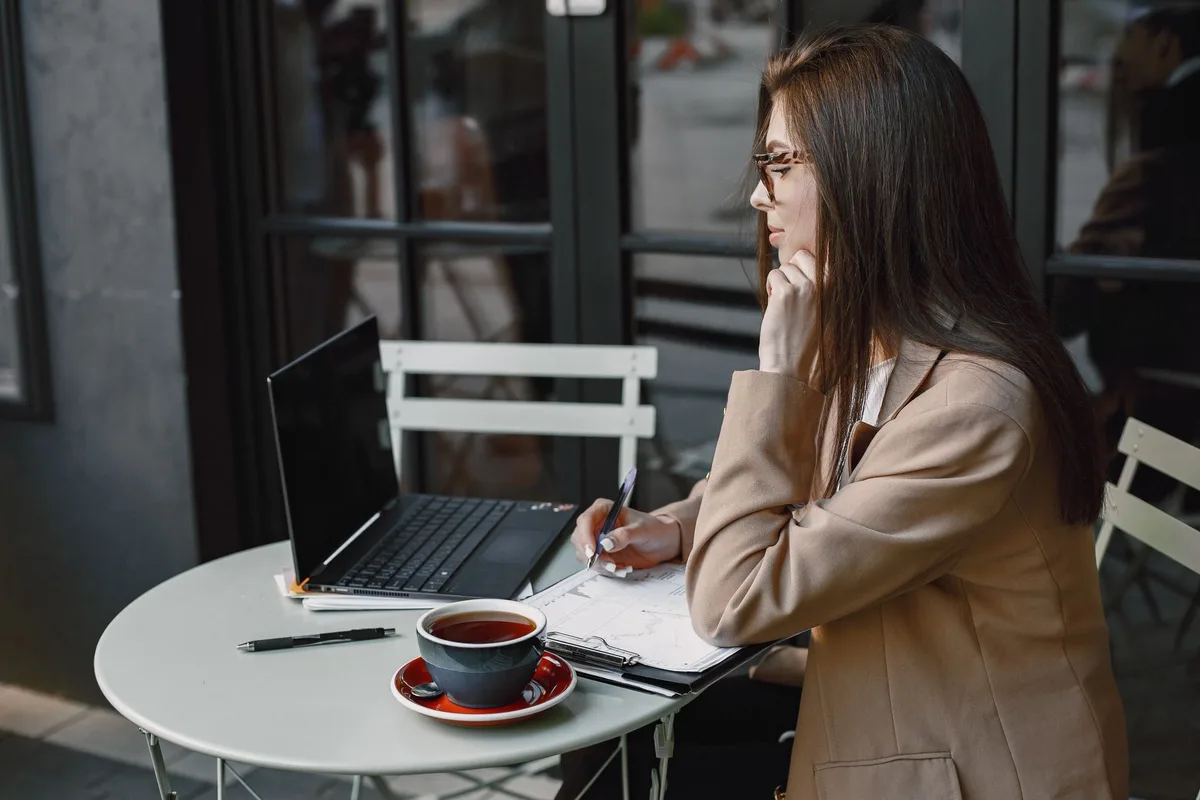 Creator working at a laptop in a coffee shop, planning a quiz lead magnet before opening a quiz builder