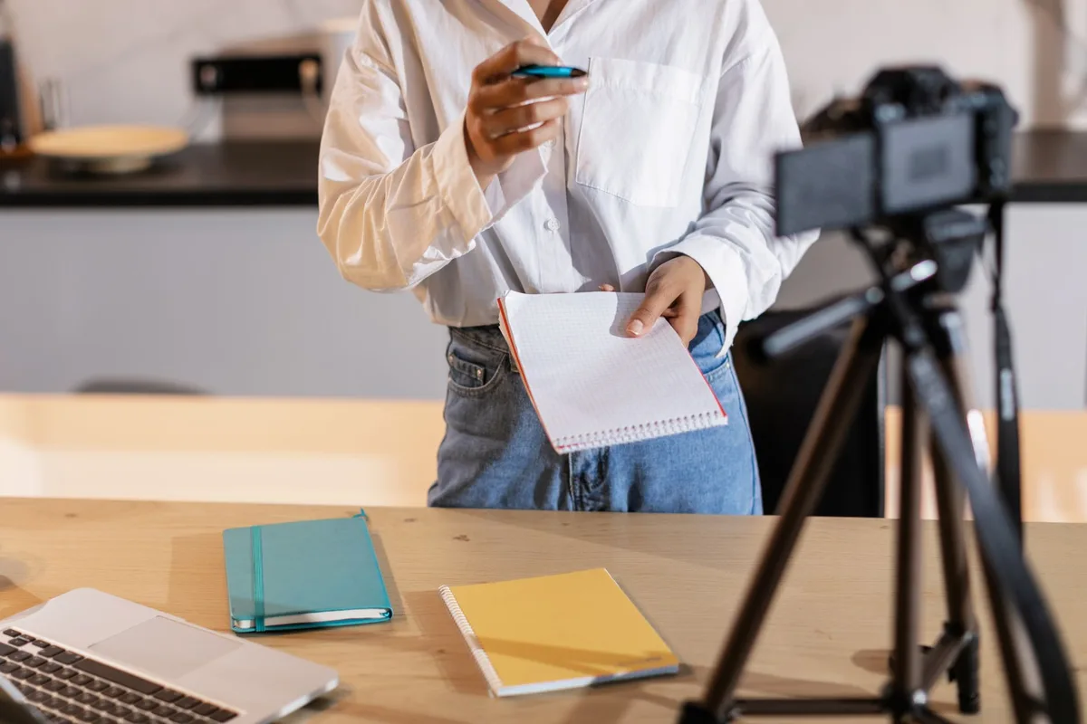 Creator organizing writing examples and notes at a desk with a laptop