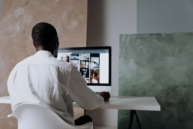 A man sitting at a computer workstation, representing a visitor spending time on a personal brand&rsquo;s About page